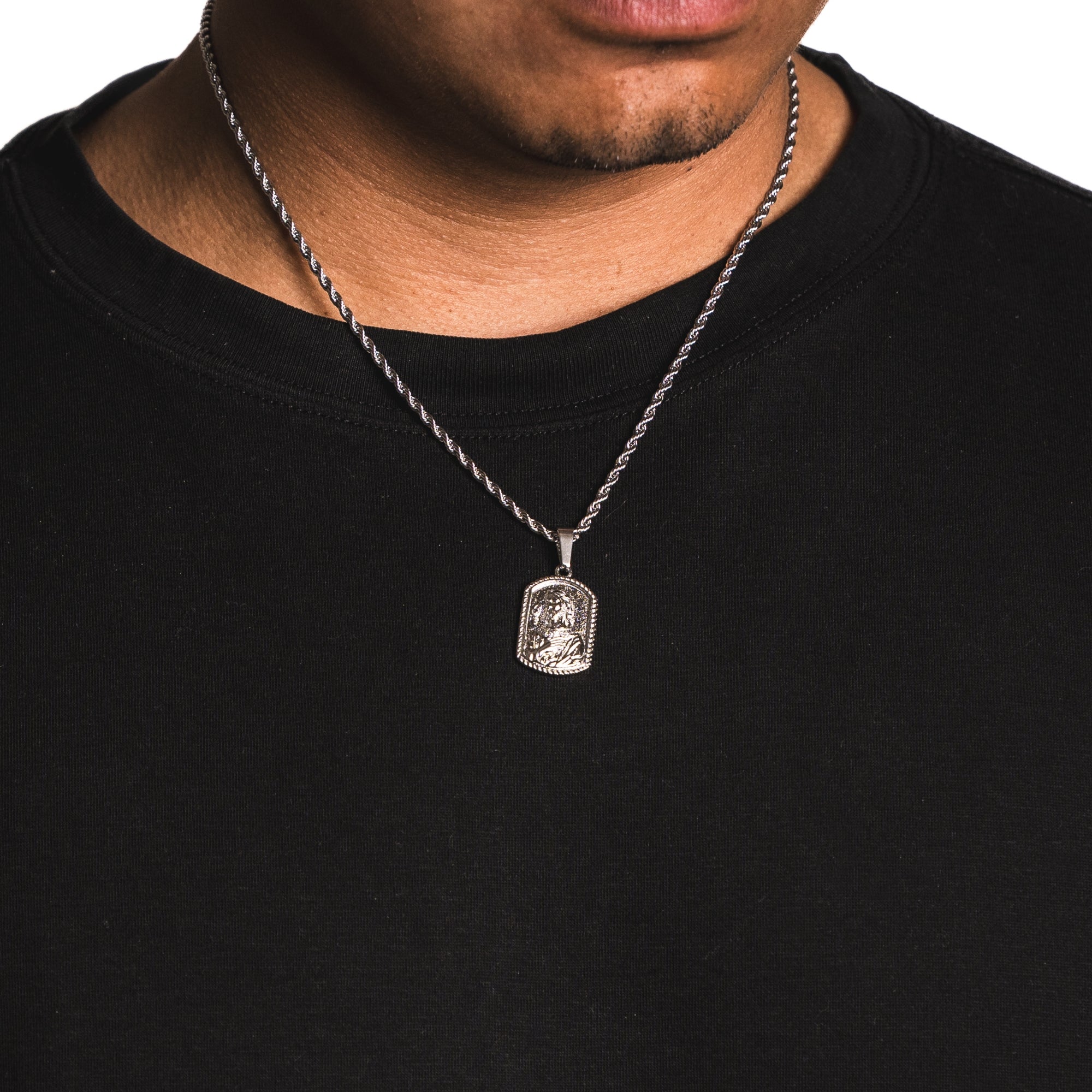 Silver necklace with a pendant worn by a person on a black background