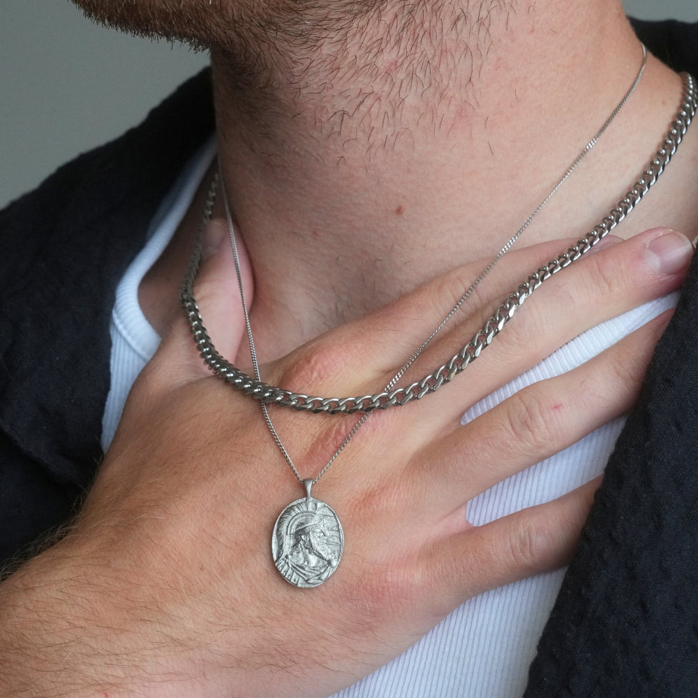 Close-up of a person wearing a silver chain necklace with a pendant.