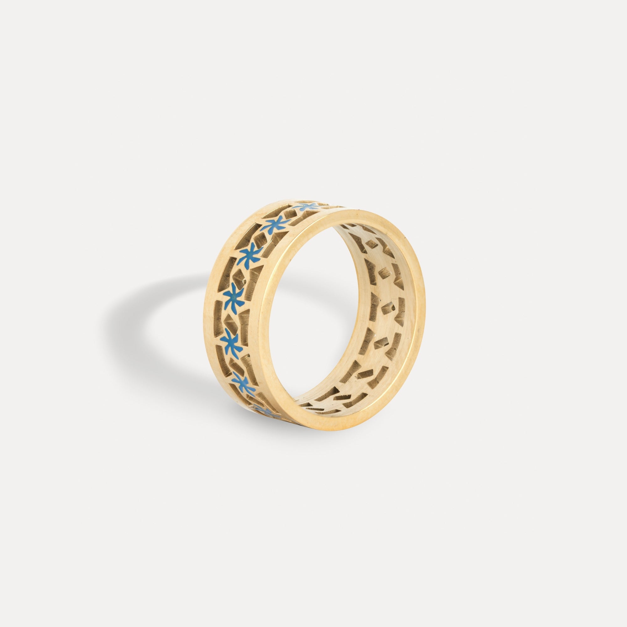 Gold ring with blue floral patterns on a light gray background