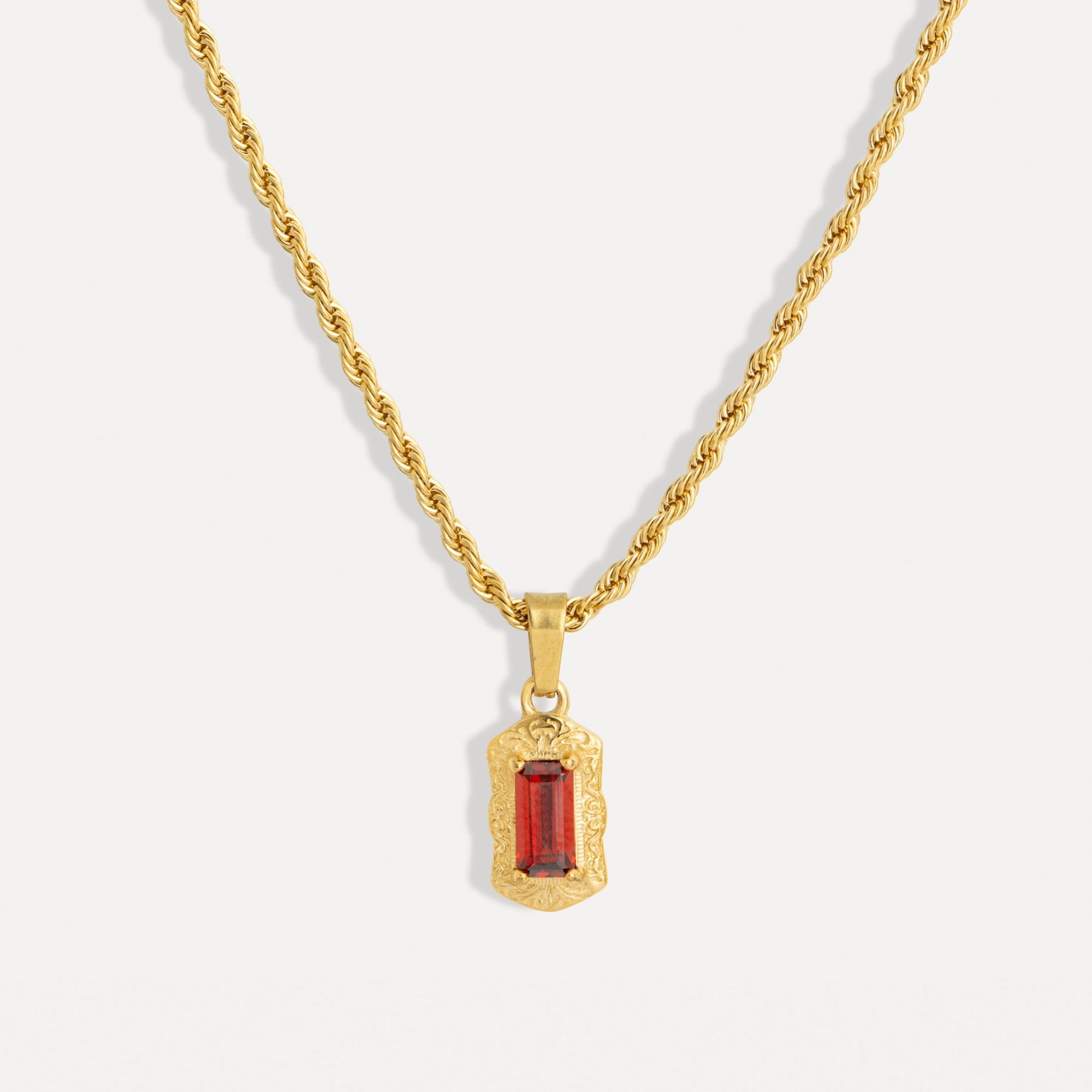 Gold necklace with a red gemstone pendant on a white background