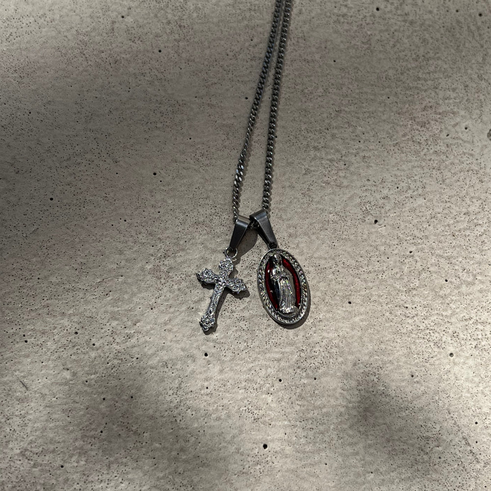 Two pendants on a chain against a textured gray background