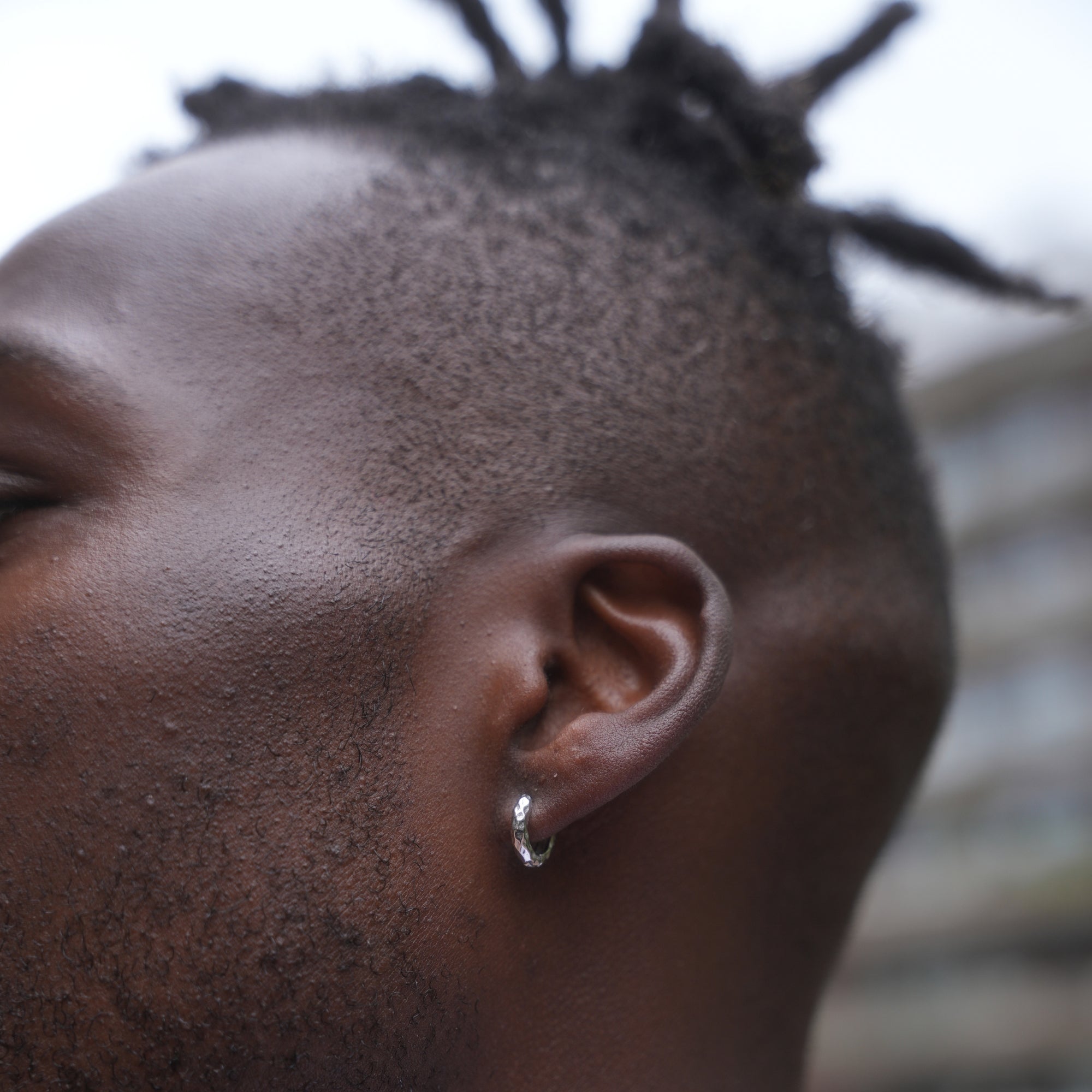 Close-up of a person's ear with an earring, blurred background