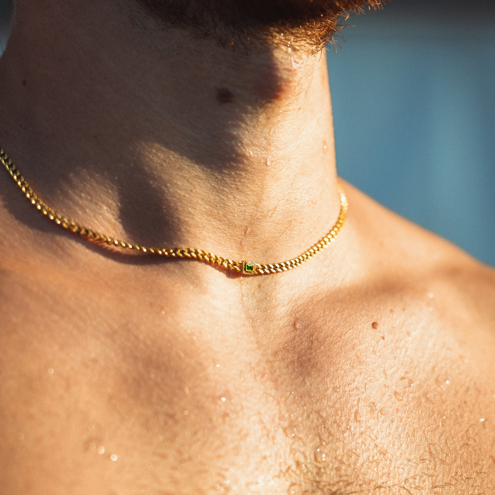 Close-up of a person wearing a gold chain necklace with a blurred background