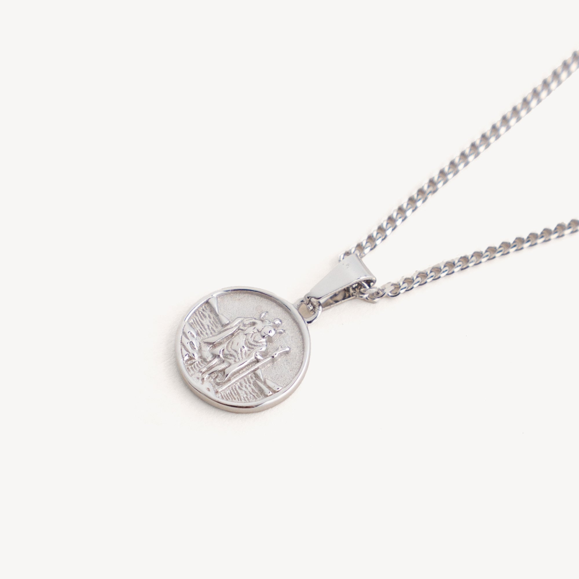 Silver necklace with a round pendant on a white background