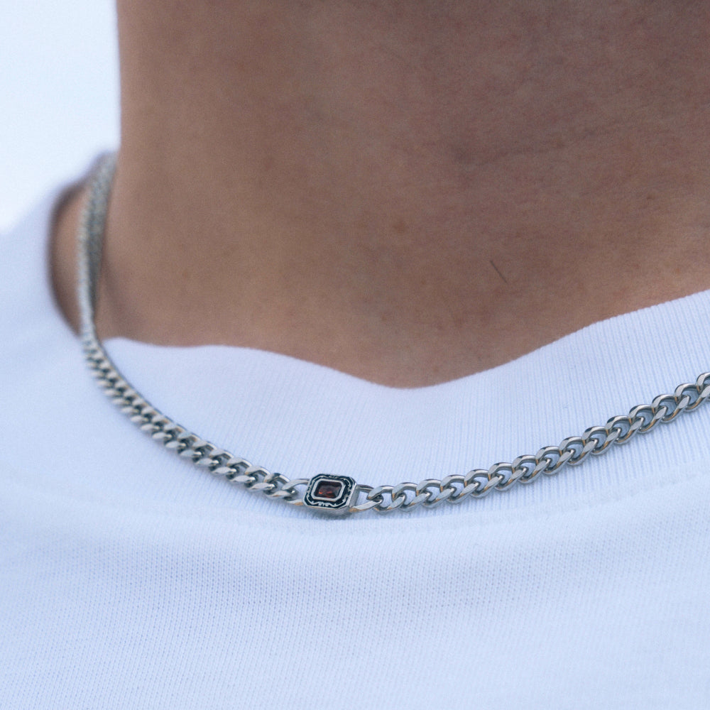 Silver chain necklace with a small black square pendant on a white background