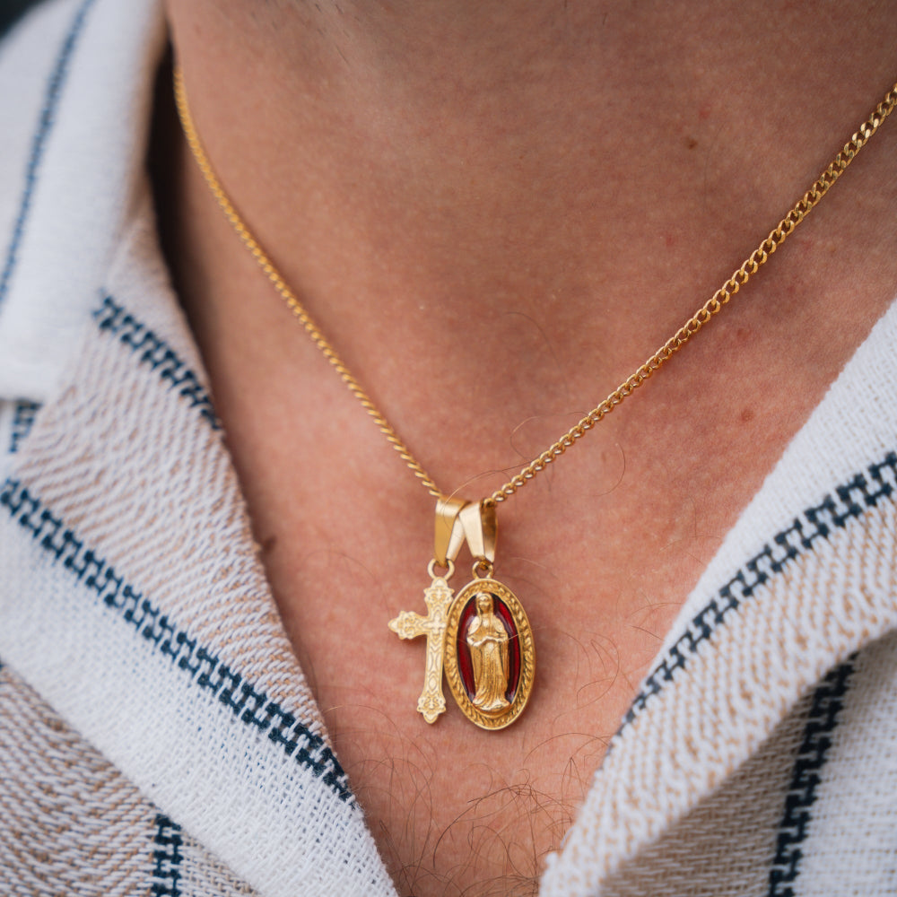 Gold necklace with a pendant featuring a religious design on a person's neck.