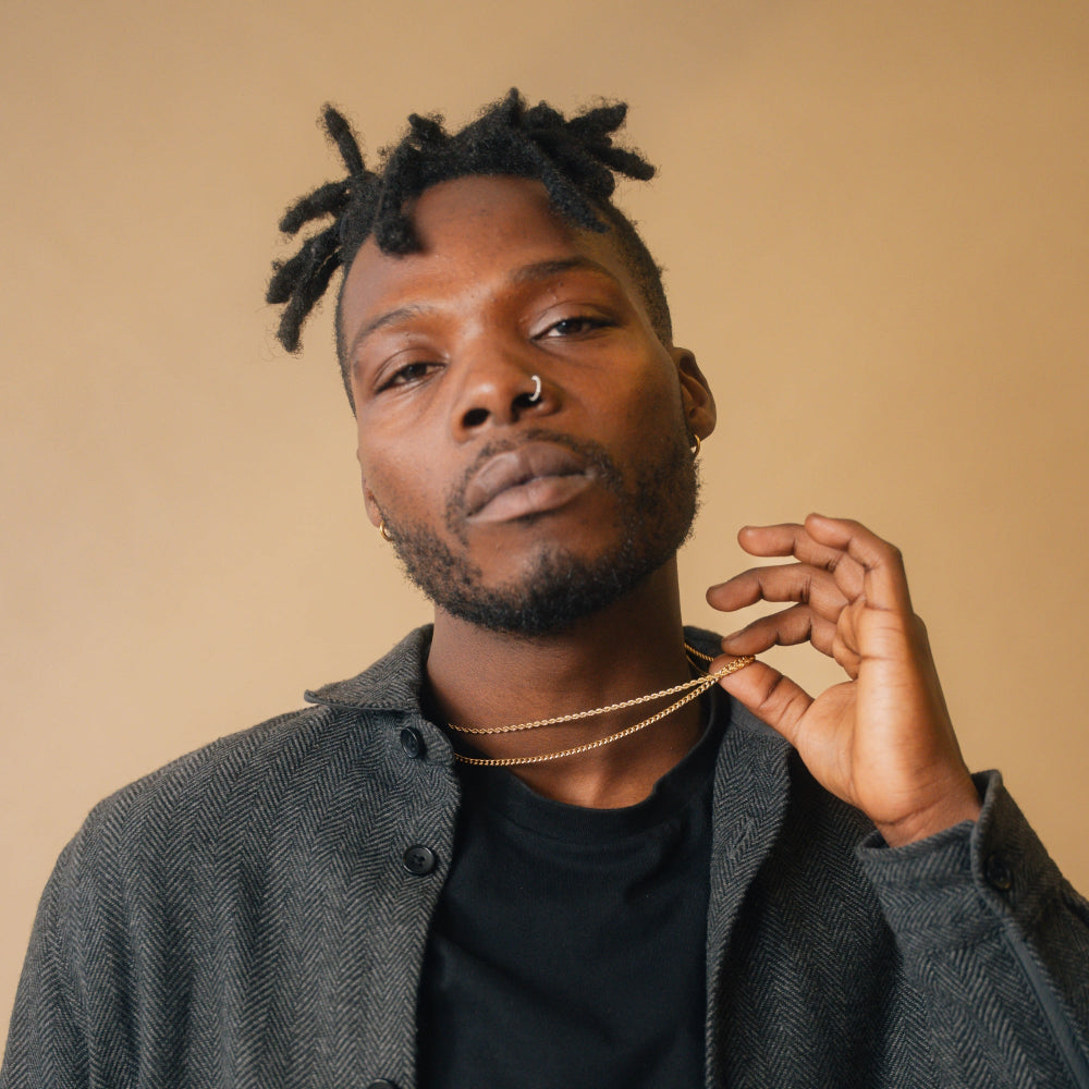 Man with styled hair and a gray jacket against a beige background