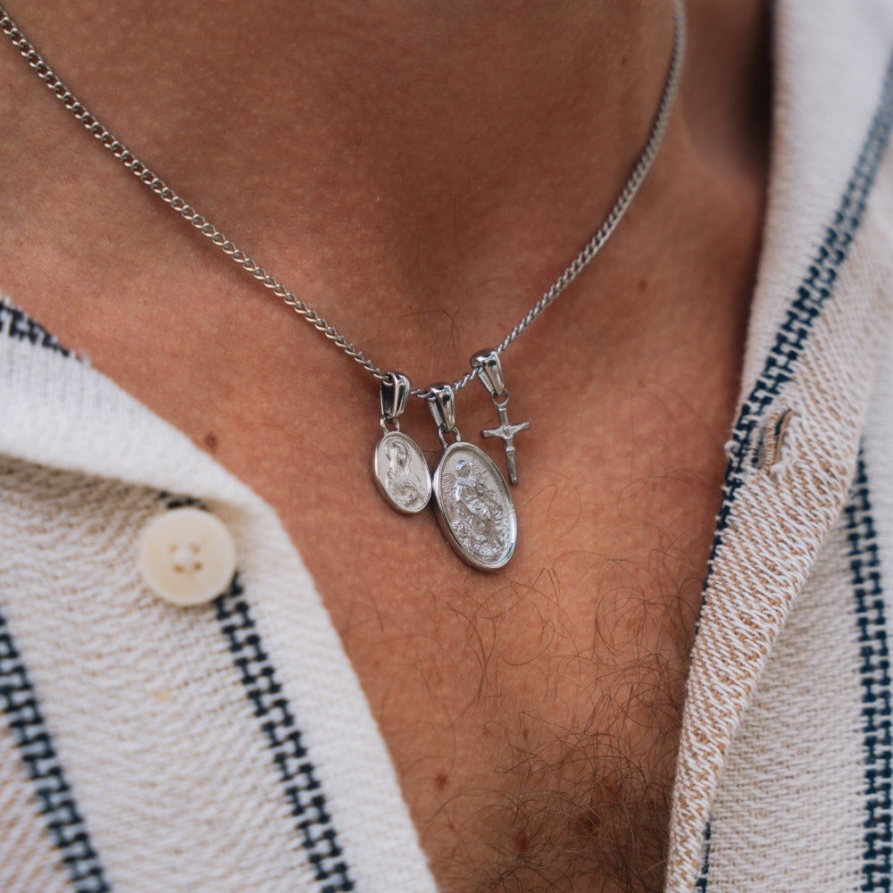 Silver necklace with two pendants on a person wearing a striped shirt.