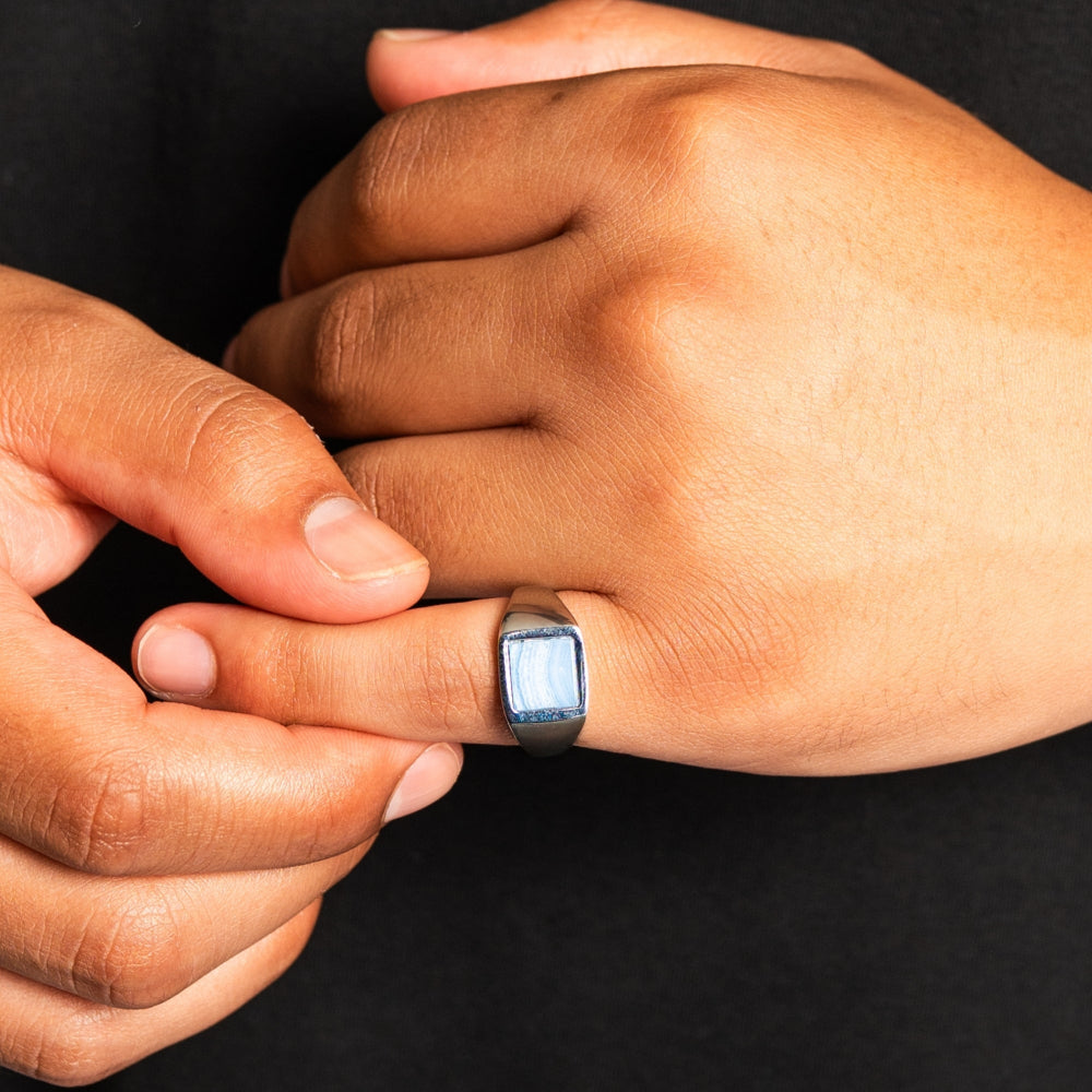 Close-up of two hands with a ring on a black background