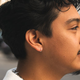 Close-up of a person wearing a silver hoop earring with a blurred background