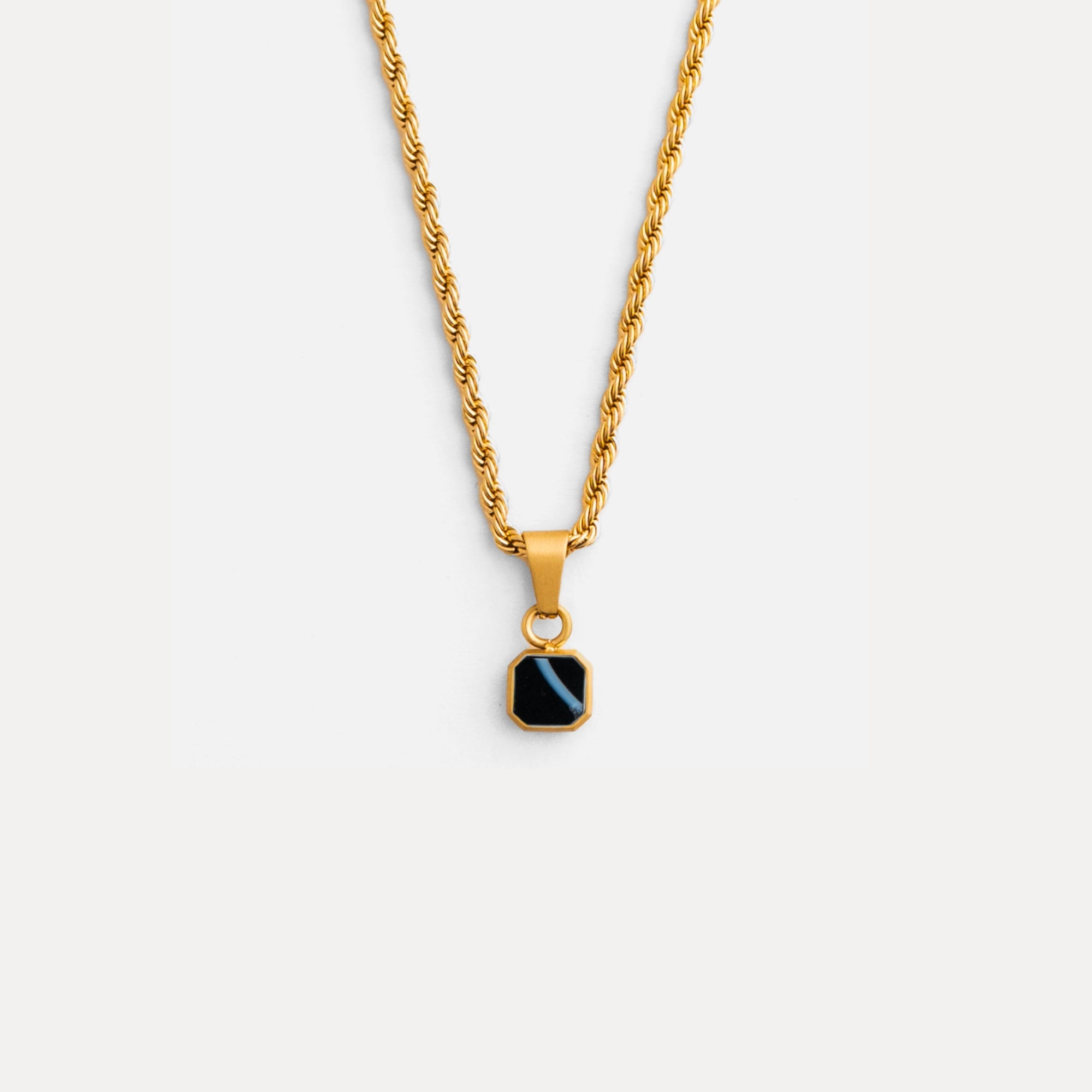 Gold necklace with a black pendant on a white background