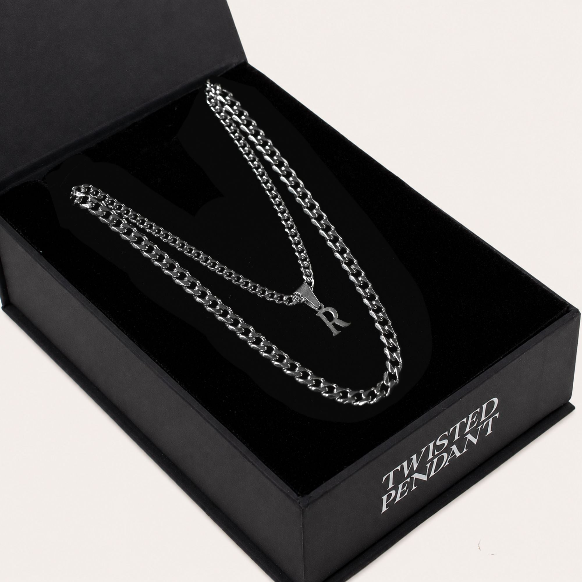 A silver-toned chain necklace with a pendant displayed inside an open black presentation box. The box lid is open and the front corner reads 'TWISTED PENDANT' in white lettering.