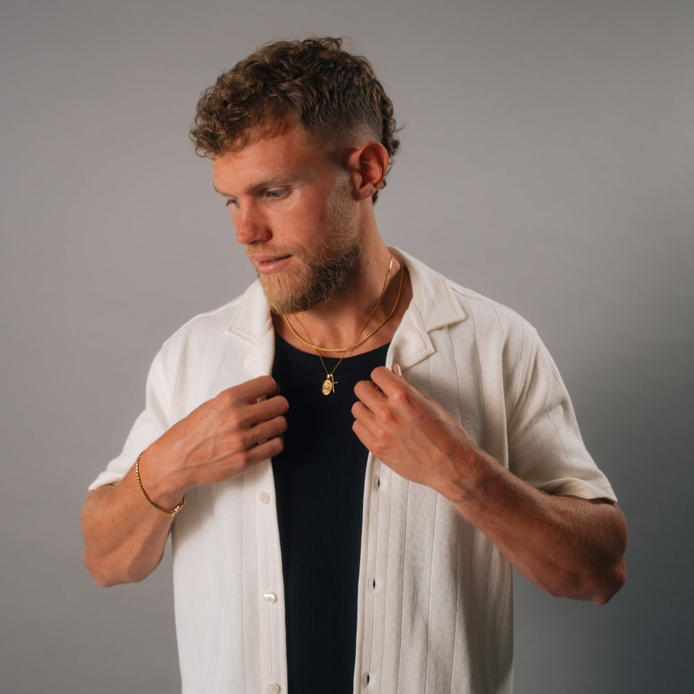 Man adjusting his white shirt against a gray background