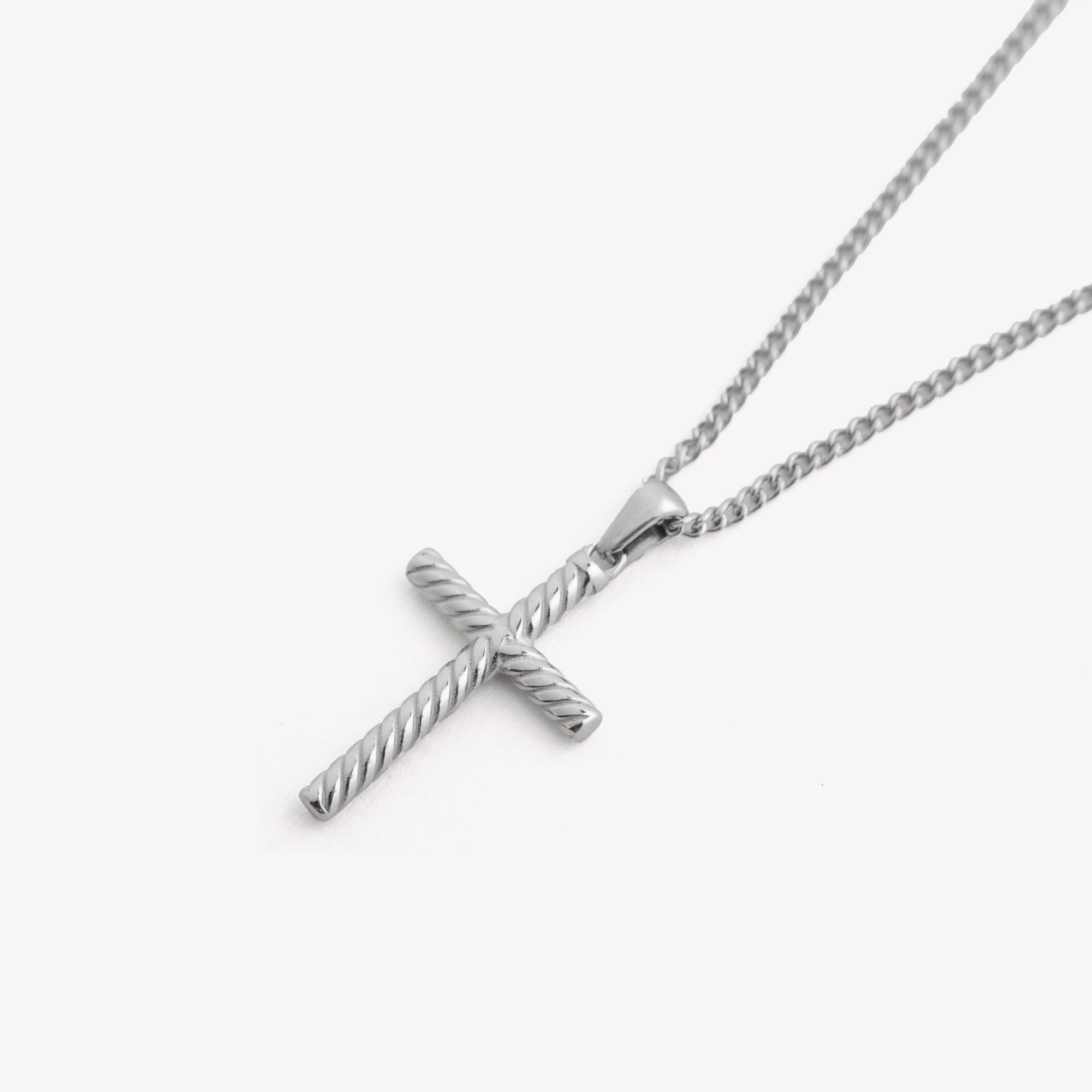 Silver cross pendant on a chain against a white background