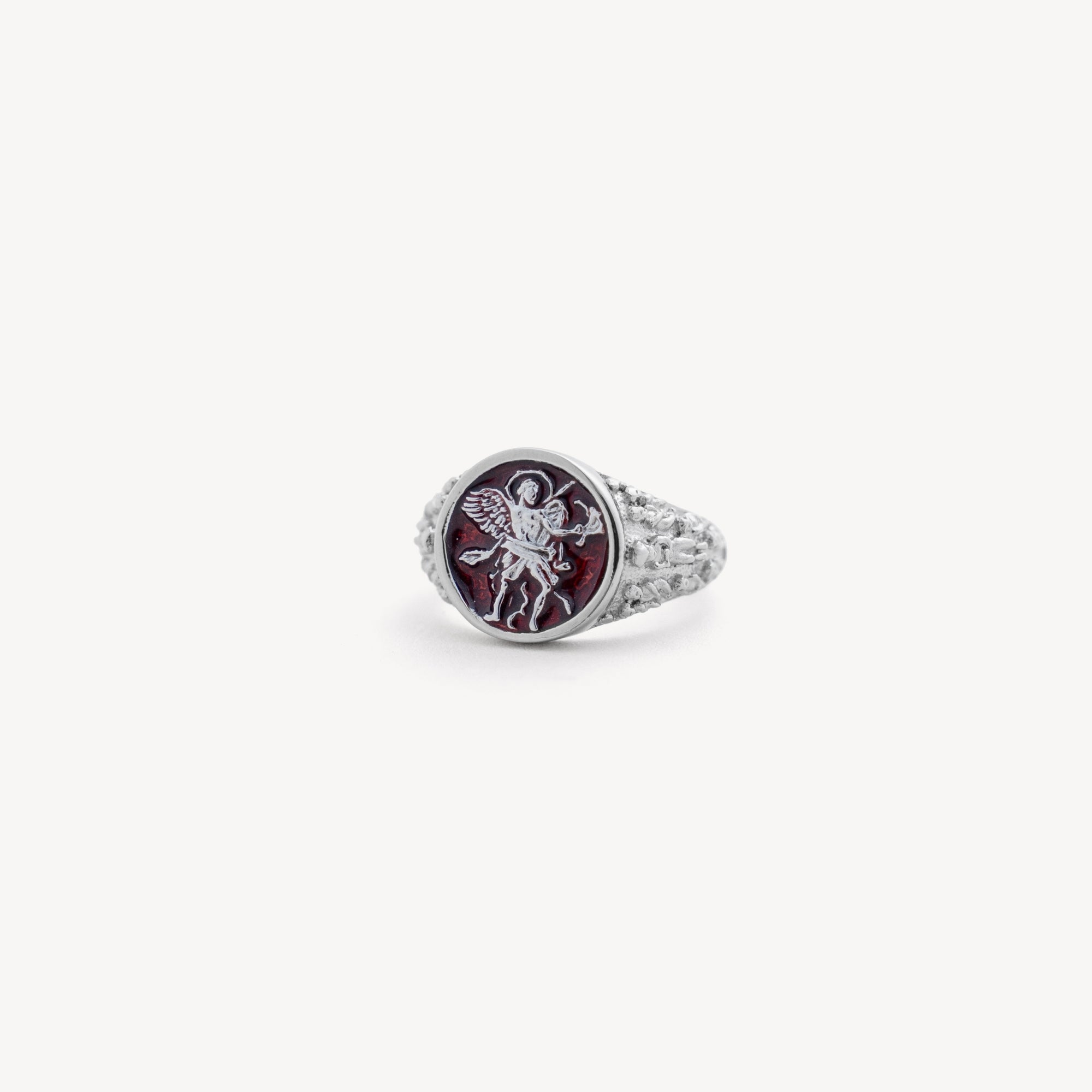 Silver ring with a red gemstone and engraved design on a white background