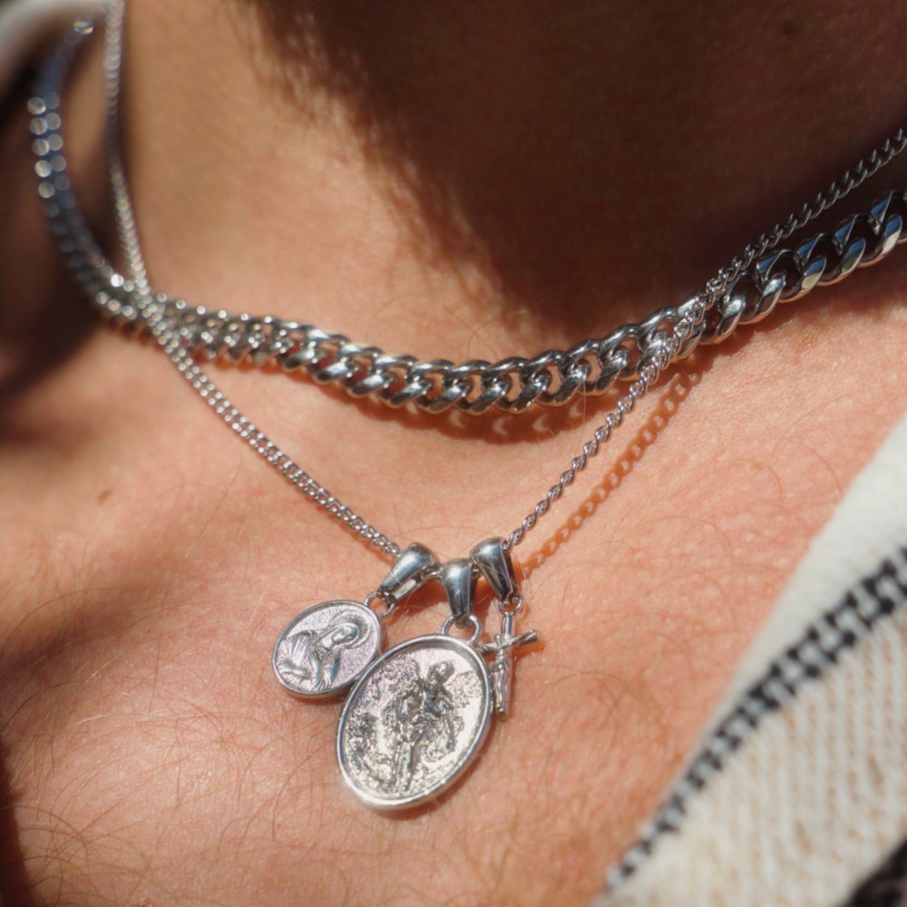 Close-up of a person wearing a silver necklace with two pendants.