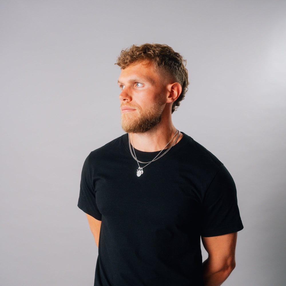 Man wearing a black t-shirt against a gray background