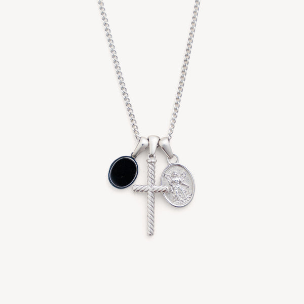 Silver necklace with three charms on a white background