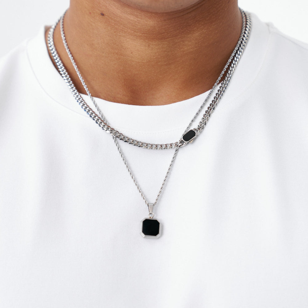 Two silver necklaces with black pendants on a white background