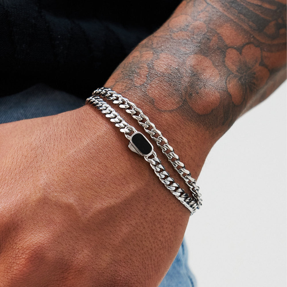 Silver chain bracelet on a tattooed arm with a blurred background