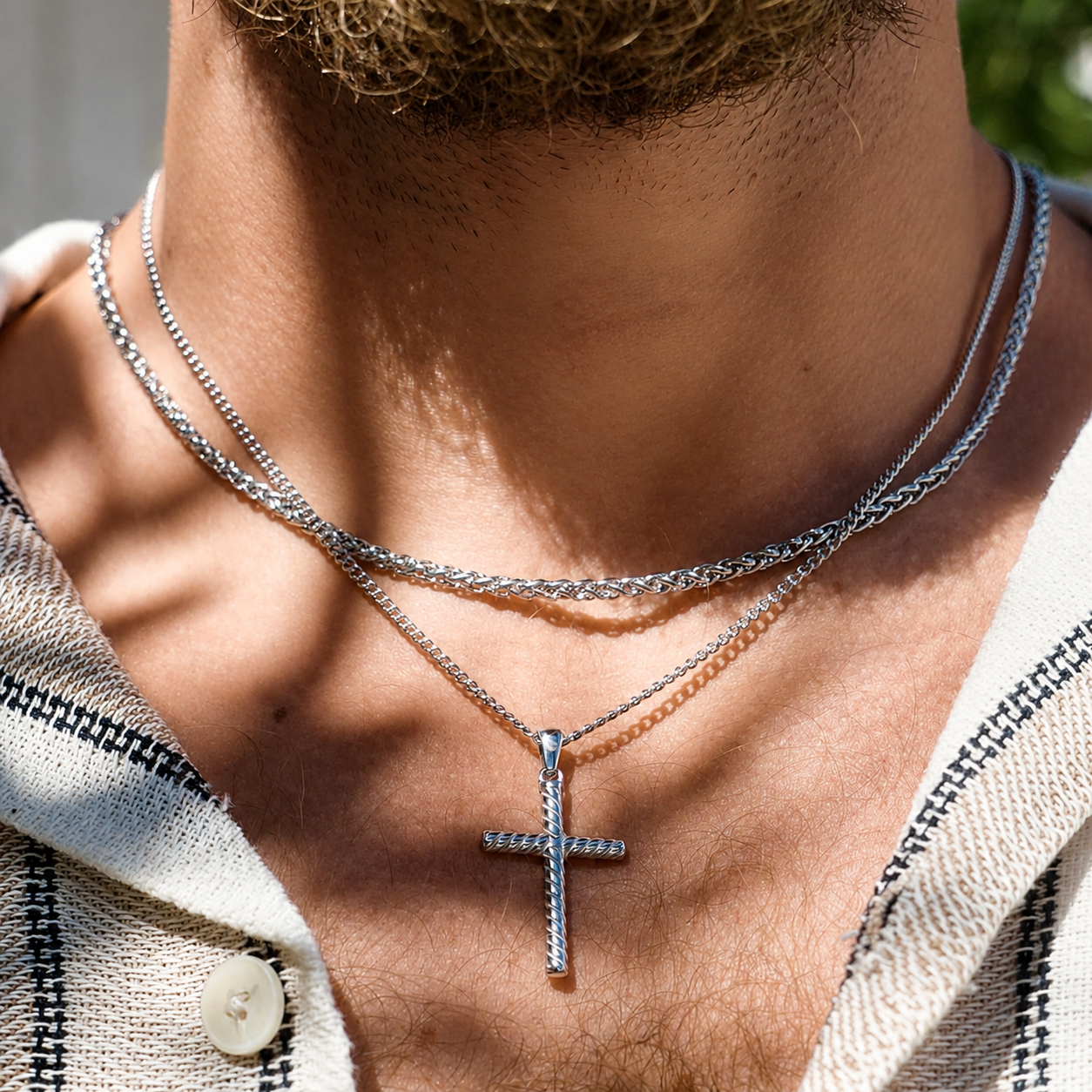 Close-up of a person wearing multiple necklaces with a cross pendant.