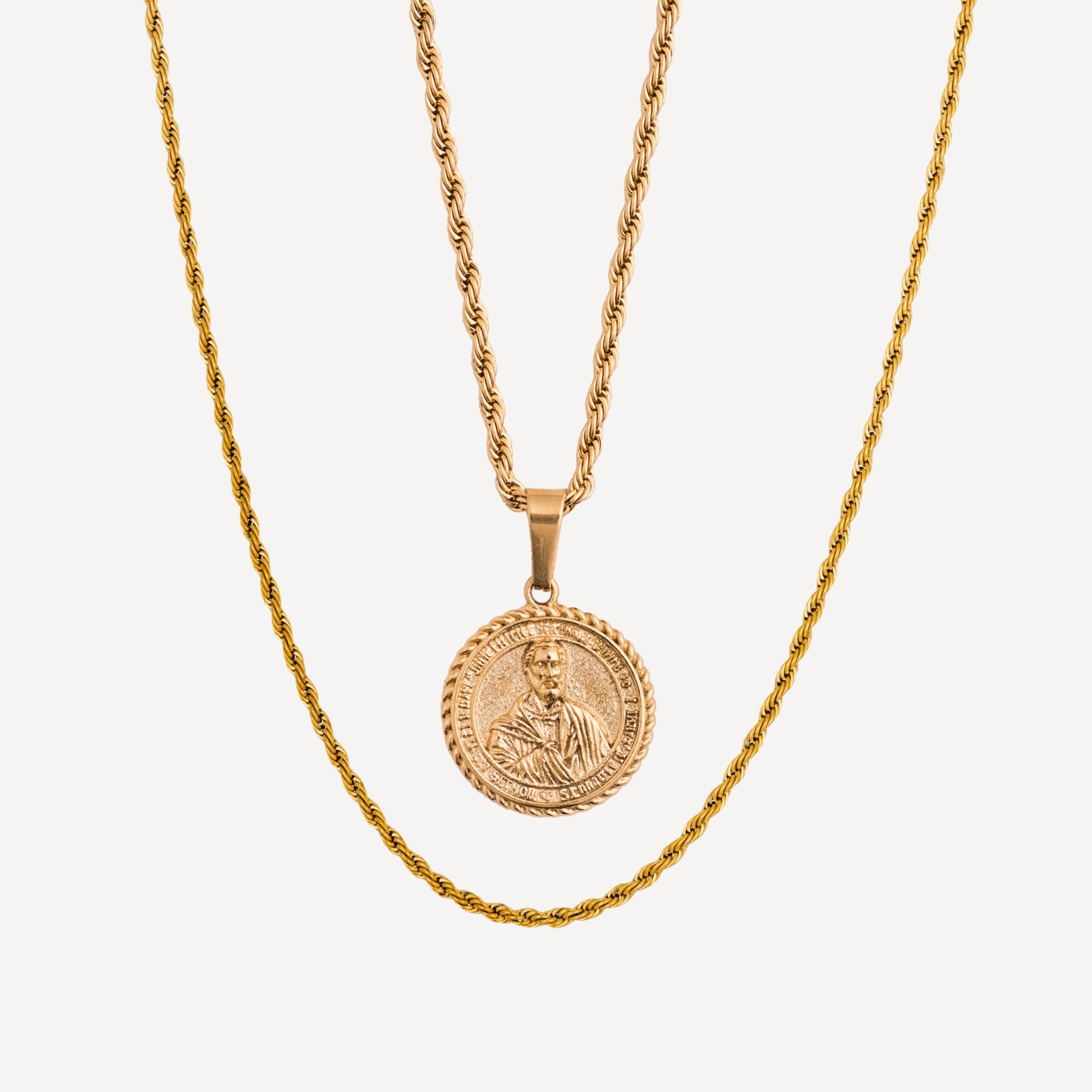 Gold necklace with a coin pendant on a light gray background